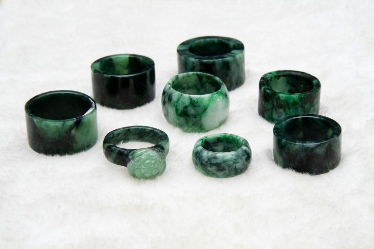 A collection of elegant jade rings displayed on a soft, plush surface, showcasing rich green hues.