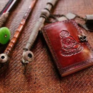 A collection of vintage Buddhist artifacts including a leather book and pipes on a textured surface.
