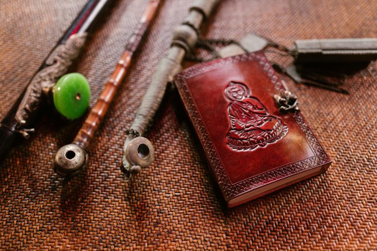 A collection of vintage Buddhist artifacts including a leather book and pipes on a textured surface.