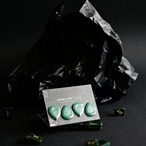 Green guitar picks displayed on a black backdrop with a dark, artistic theme.