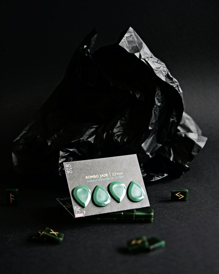 Green guitar picks displayed on a black backdrop with a dark, artistic theme.