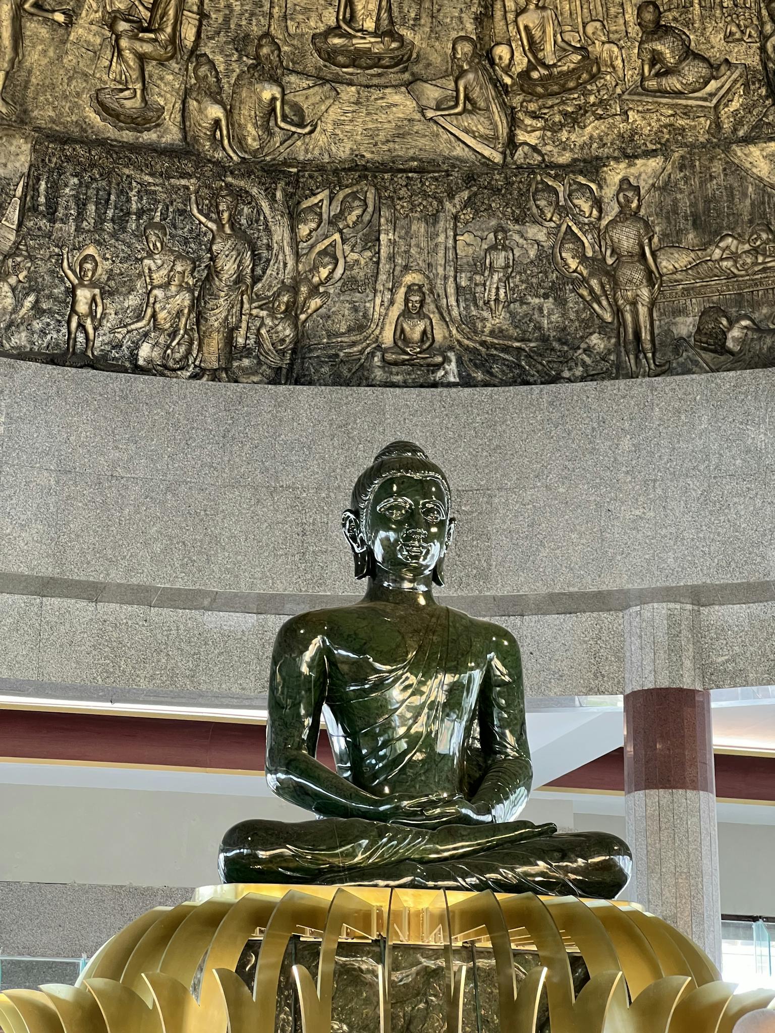 Jade Buddha sculpture with intricate carvings in a serene indoor setting.